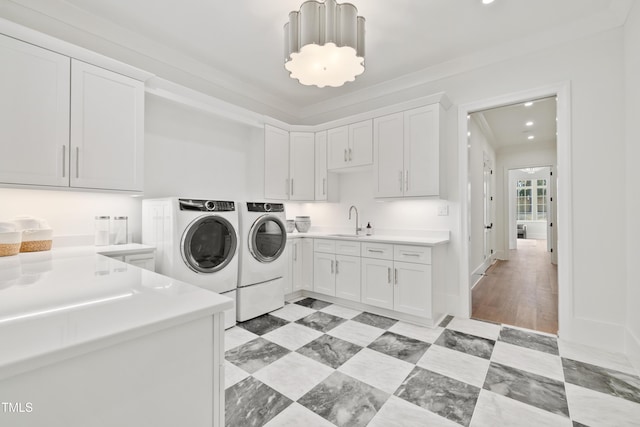 laundry area featuring cabinets, crown molding, independent washer and dryer, and sink