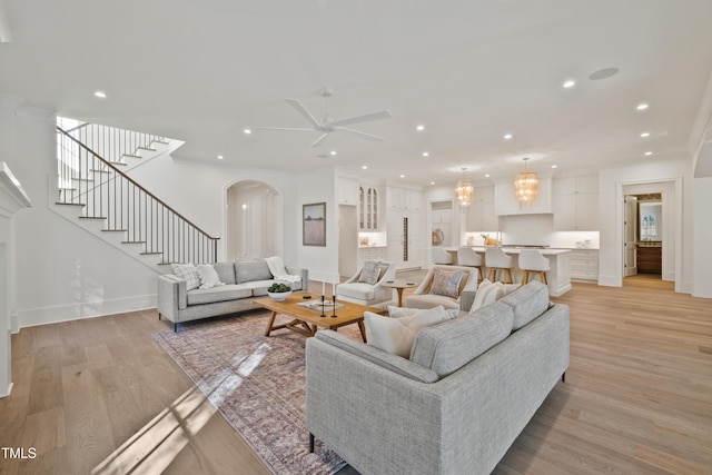 living room featuring ceiling fan, ornamental molding, and light wood-type flooring