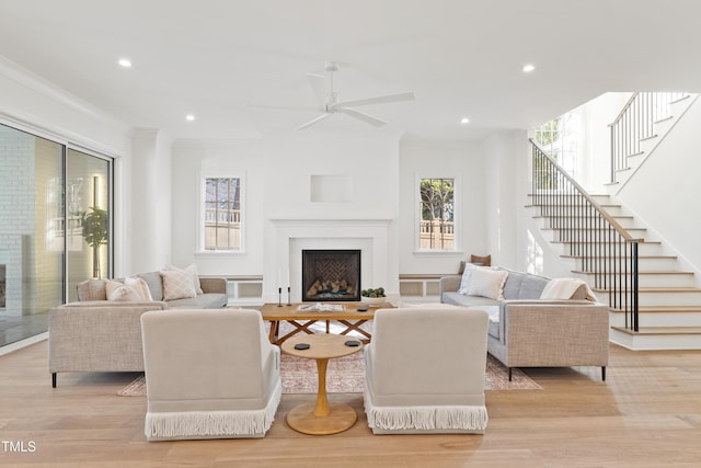 living room with ceiling fan, ornamental molding, and light wood-type flooring