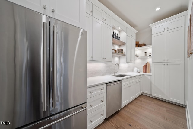 kitchen featuring appliances with stainless steel finishes, white cabinetry, tasteful backsplash, and sink