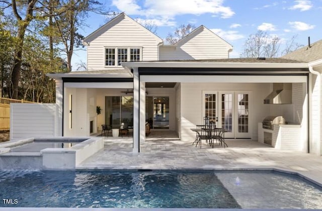 back of house featuring a swimming pool with hot tub, ceiling fan, a patio area, an outdoor kitchen, and french doors