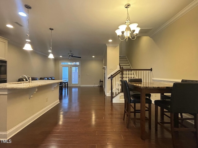 dining area featuring dark wood-type flooring, french doors, ornamental molding, ceiling fan with notable chandelier, and sink