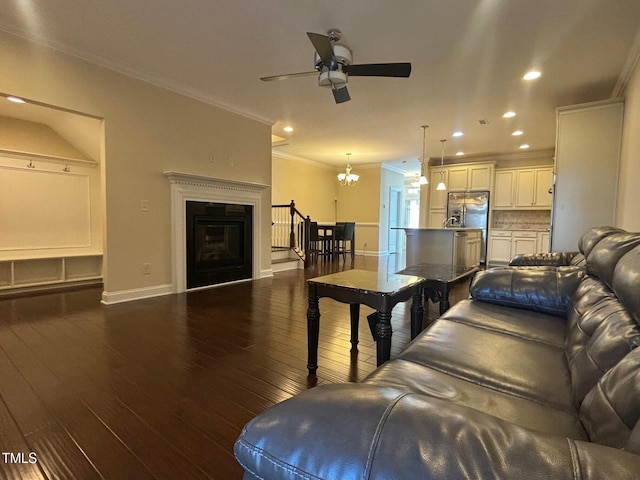 living room with dark wood-type flooring, crown molding, and ceiling fan with notable chandelier