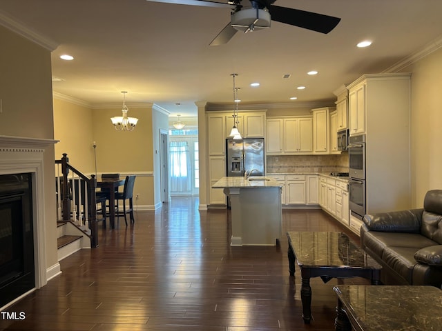 kitchen featuring pendant lighting, decorative backsplash, a kitchen island with sink, stainless steel appliances, and light stone counters