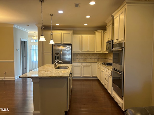 kitchen featuring a center island with sink, appliances with stainless steel finishes, tasteful backsplash, decorative light fixtures, and sink