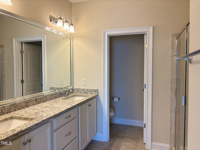 bathroom featuring toilet, vanity, tile patterned flooring, and a shower with door