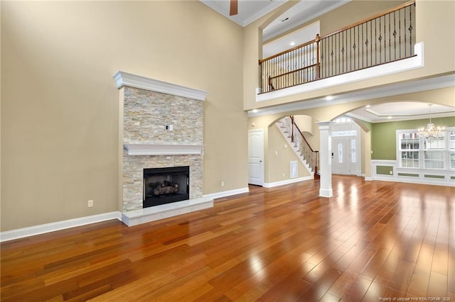 unfurnished living room with crown molding, hardwood / wood-style flooring, a fireplace, and a high ceiling