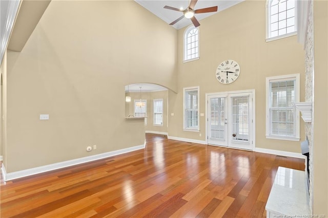 unfurnished living room with french doors, ceiling fan, hardwood / wood-style floors, and a high ceiling