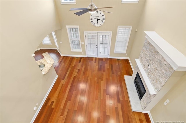 unfurnished living room featuring hardwood / wood-style flooring, a towering ceiling, and ceiling fan