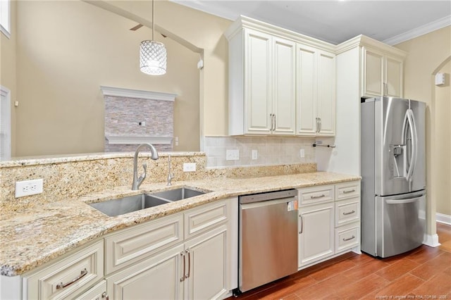 kitchen with sink, hanging light fixtures, light stone counters, stainless steel appliances, and crown molding