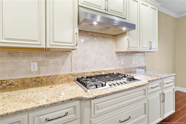 kitchen with tasteful backsplash, white cabinetry, stainless steel gas cooktop, light stone counters, and crown molding