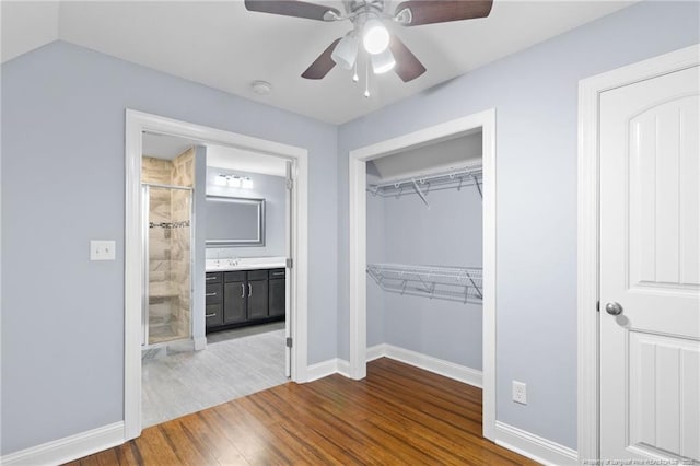 unfurnished bedroom featuring sink, ceiling fan, hardwood / wood-style floors, connected bathroom, and a closet