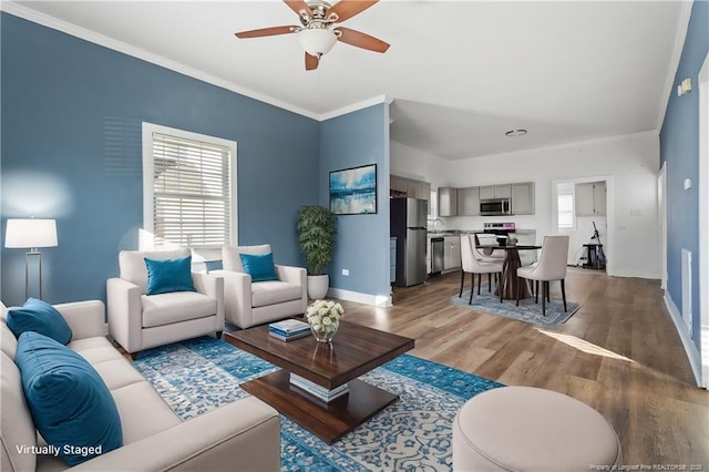 living room with ceiling fan, light wood-type flooring, plenty of natural light, and ornamental molding