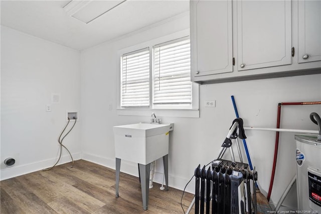 washroom with electric water heater, radiator, washer hookup, cabinets, and light hardwood / wood-style flooring