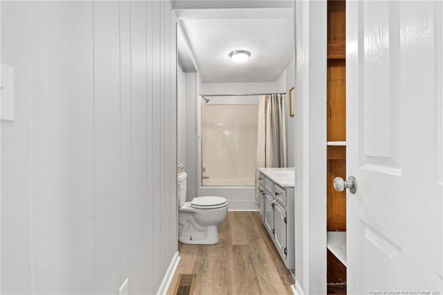 full bathroom with toilet, shower / bath combo with shower curtain, wood-type flooring, a textured ceiling, and vanity