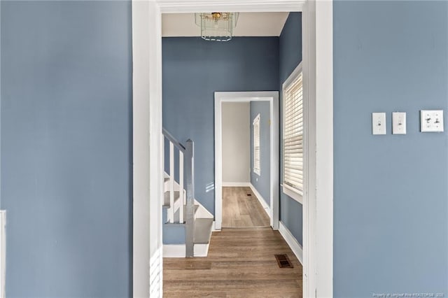 hallway featuring wood-type flooring and a notable chandelier