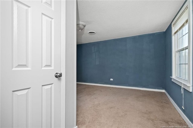 carpeted empty room featuring a textured ceiling