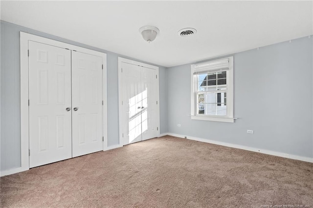 unfurnished bedroom with carpet flooring and multiple closets