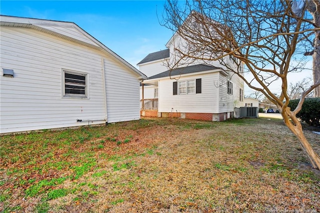 rear view of house with central air condition unit and a lawn