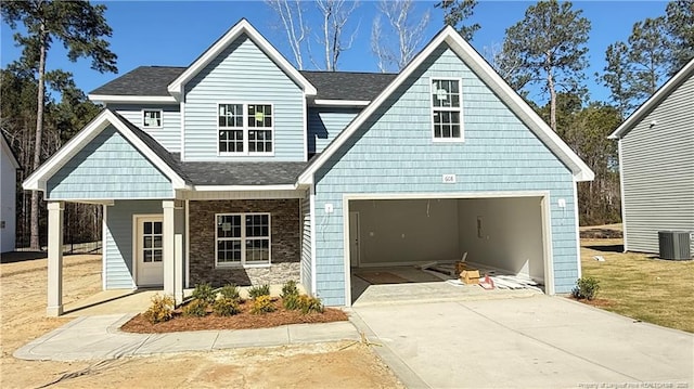 view of front of house with driveway, a garage, a shingled roof, stone siding, and cooling unit