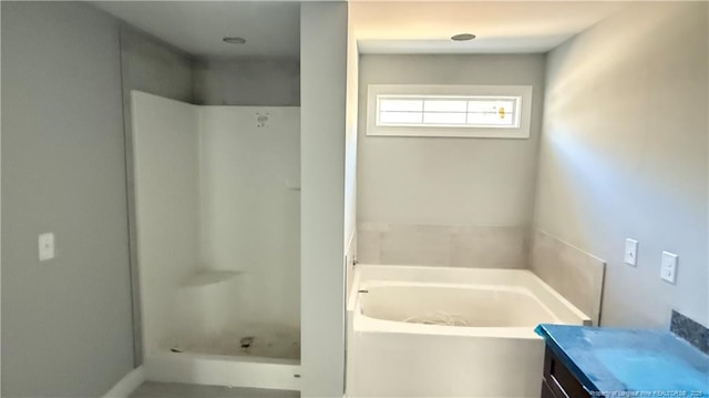 full bathroom featuring a stall shower, a garden tub, and vanity