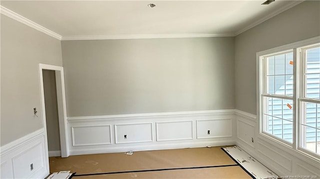 empty room featuring a wainscoted wall and ornamental molding