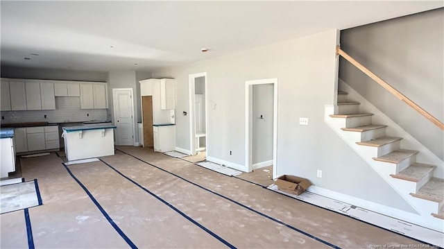 kitchen featuring tasteful backsplash, white cabinetry, baseboards, and a center island