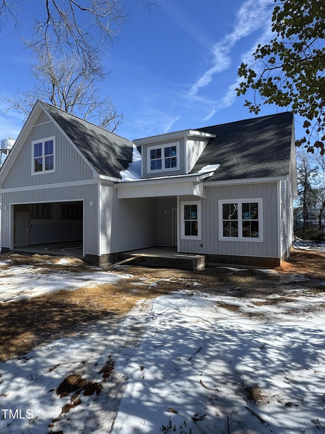 view of front facade with a garage, covered porch, and a shingled roof