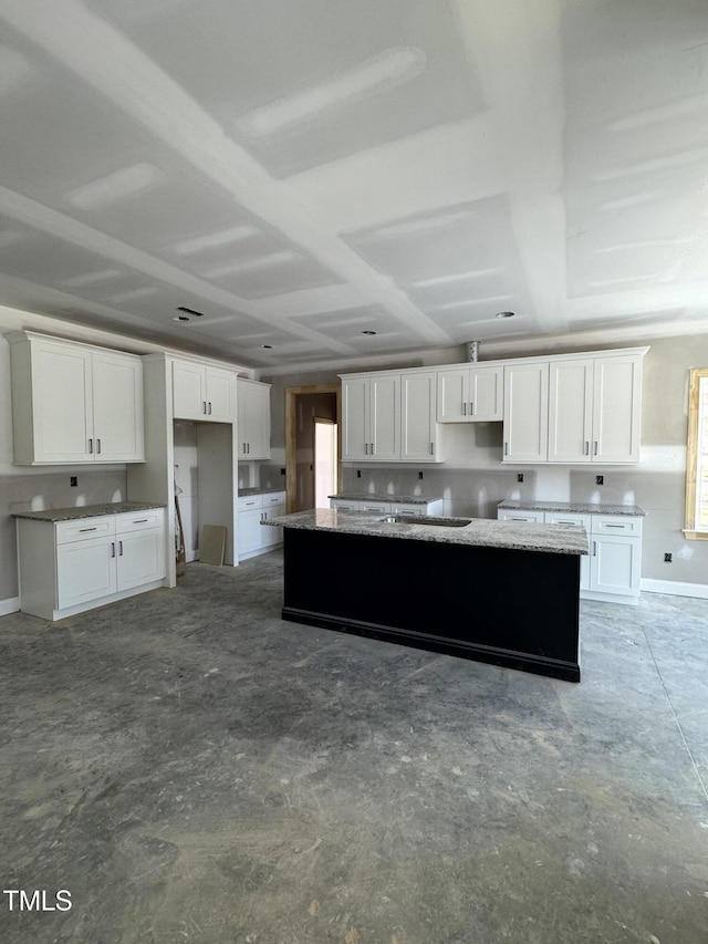 kitchen featuring a kitchen island, white cabinets, and unfinished concrete flooring