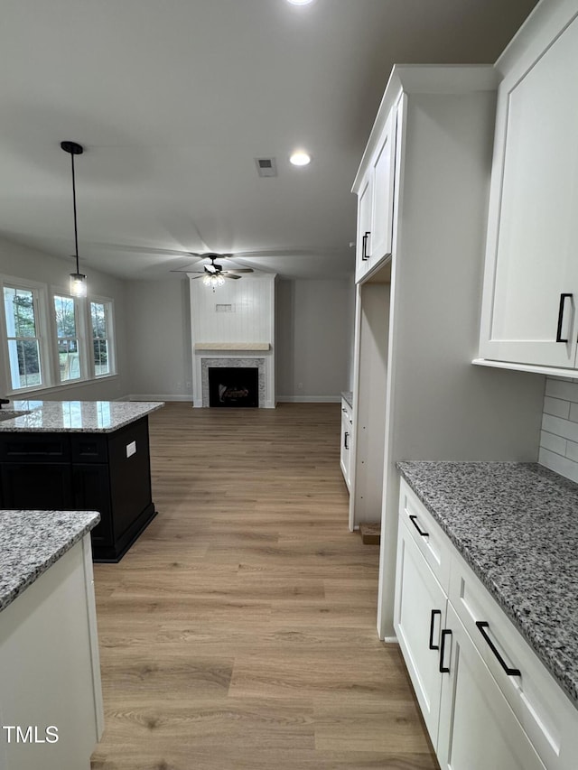 504 Tucker St, Four Oaks, NC 27524 - kitchen with ceiling fan, light wood finished floors, visible vents, white cabinets, and a fireplace