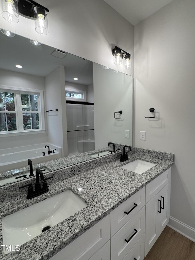 504 Tucker St, Four Oaks, NC 27524 - bathroom featuring double vanity, a sink, a garden tub, and wood finished floors