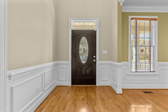 entryway with ornamental molding and light hardwood / wood-style floors