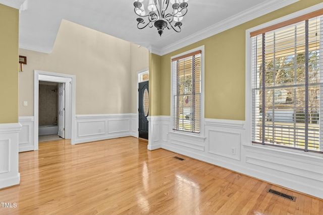 empty room featuring an inviting chandelier, ornamental molding, and hardwood / wood-style flooring