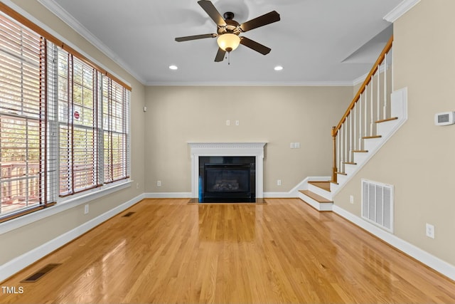 unfurnished living room featuring ceiling fan, ornamental molding, and light wood-type flooring