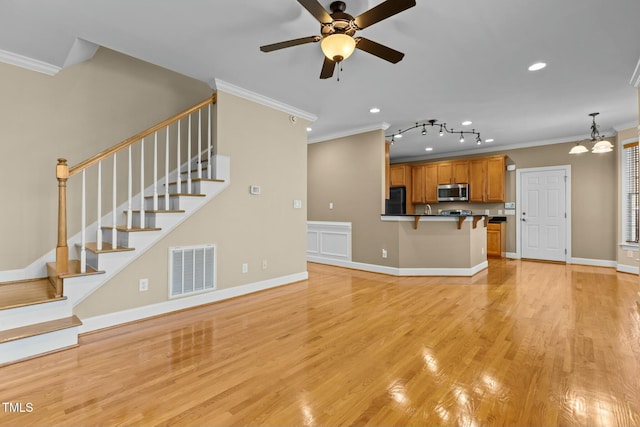 unfurnished living room with ornamental molding, ceiling fan with notable chandelier, and light hardwood / wood-style flooring