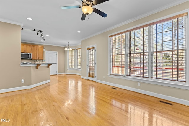 unfurnished living room with crown molding, light hardwood / wood-style flooring, and ceiling fan with notable chandelier