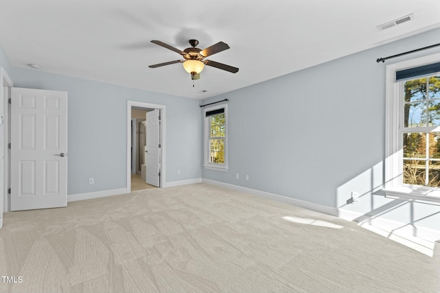 carpeted empty room with a wealth of natural light and ceiling fan