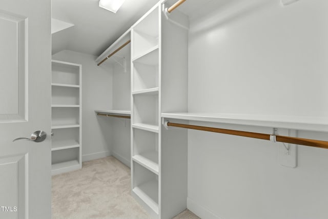 walk in closet with light carpet and lofted ceiling