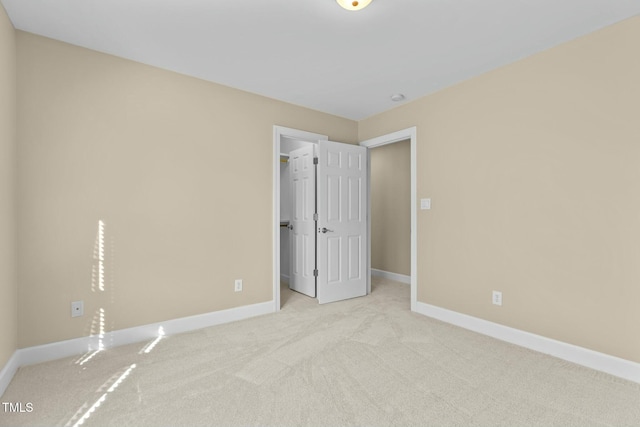 unfurnished bedroom featuring a spacious closet, light carpet, and a closet