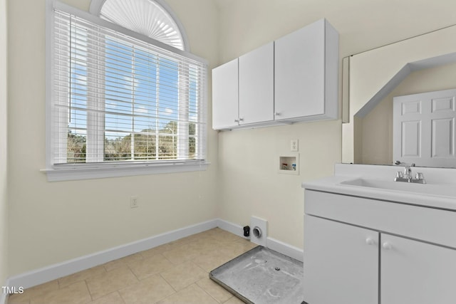 clothes washing area with cabinets, sink, washer hookup, and light tile patterned floors