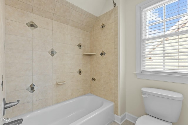 bathroom with tiled shower / bath combo and toilet