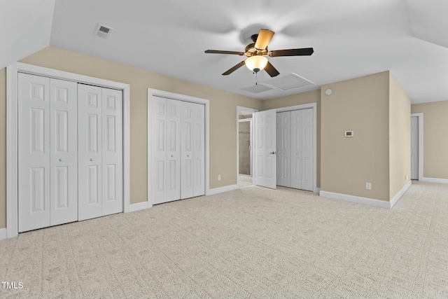 unfurnished bedroom featuring light carpet, ceiling fan, lofted ceiling, and multiple closets