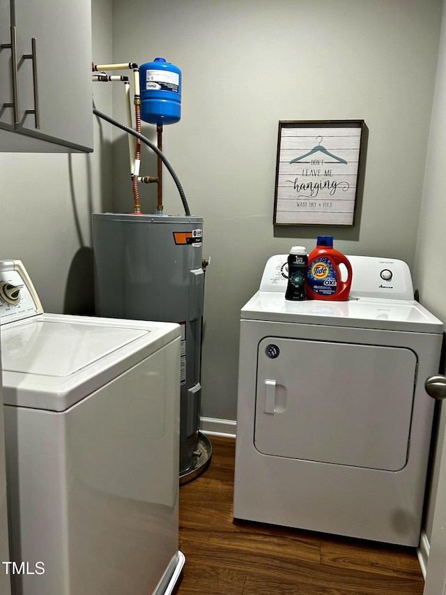 clothes washing area with cabinets, dark hardwood / wood-style floors, washing machine and dryer, and electric water heater