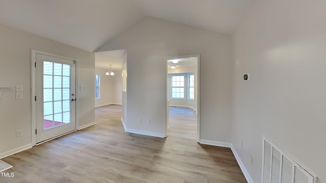 interior space with light wood-type flooring, a notable chandelier, and vaulted ceiling