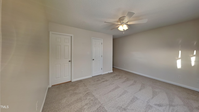 unfurnished bedroom with ceiling fan, light carpet, and a textured ceiling