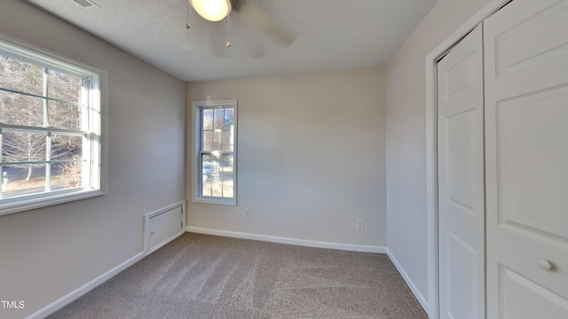 unfurnished bedroom with ceiling fan, a textured ceiling, a closet, and light carpet