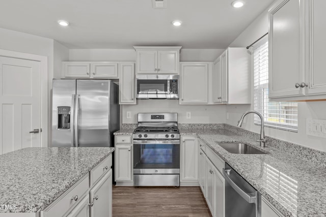 kitchen with sink, white cabinetry, light stone counters, dark hardwood / wood-style flooring, and stainless steel appliances