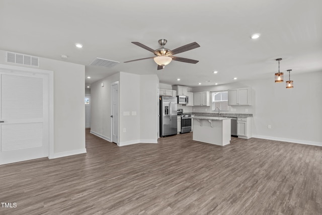 kitchen featuring appliances with stainless steel finishes, decorative light fixtures, sink, white cabinets, and a center island