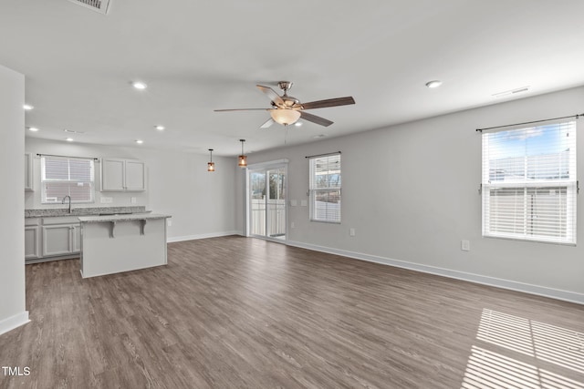 unfurnished living room featuring hardwood / wood-style flooring, sink, and ceiling fan