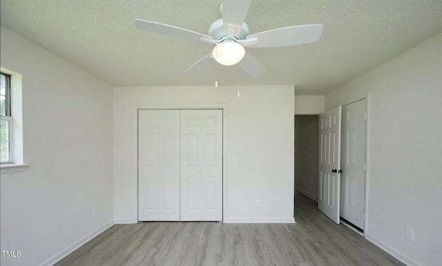 unfurnished bedroom with ceiling fan, a closet, a textured ceiling, and light wood-type flooring